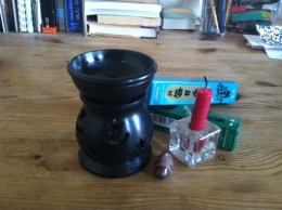 A black oil diffuser, a red candle, a small Shiva lingam stone, and two boxes of incense.